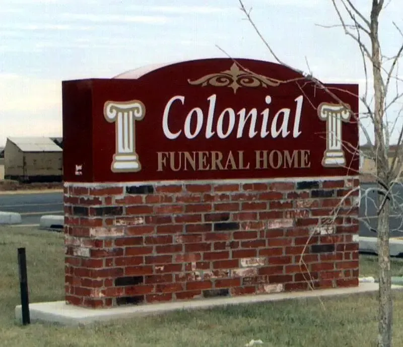 Colonial Funeral Home sign on a brick base with red and white lettering