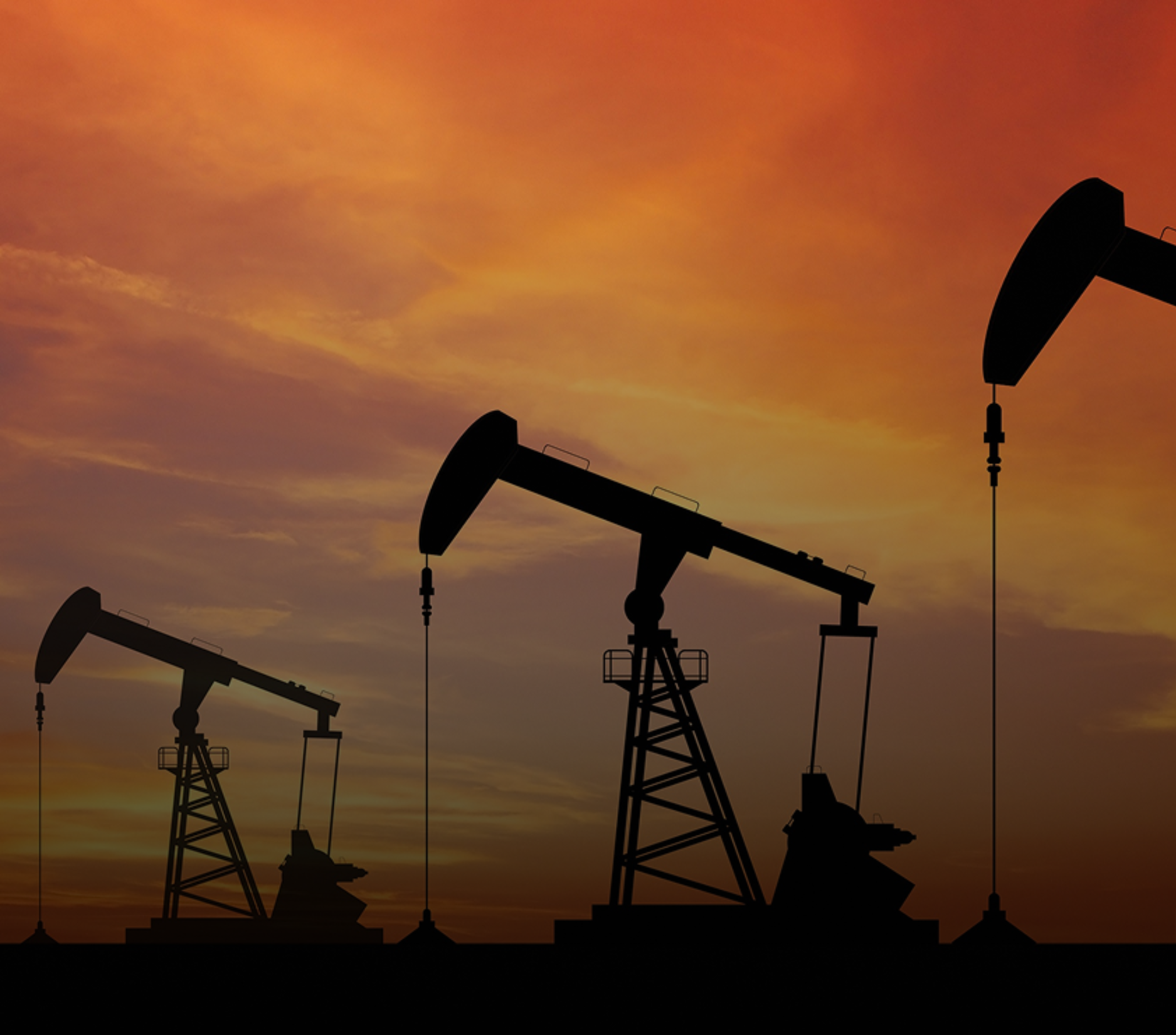 Oil pumps silhouetted against an orange and red sunset.