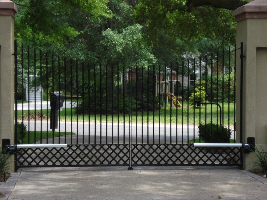 A wrought iron gate is open to a driveway