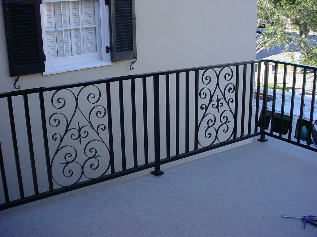 A balcony with a wrought iron railing and a window with shutters
