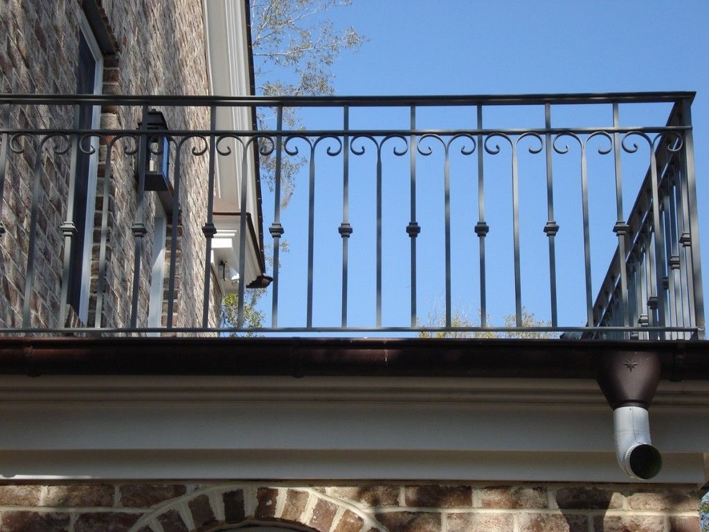 A balcony with a wrought iron railing on a brick building