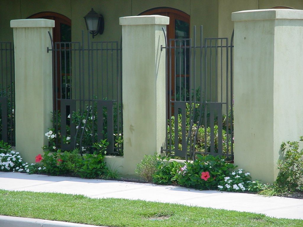 A fence surrounds a house with flowers in front of it