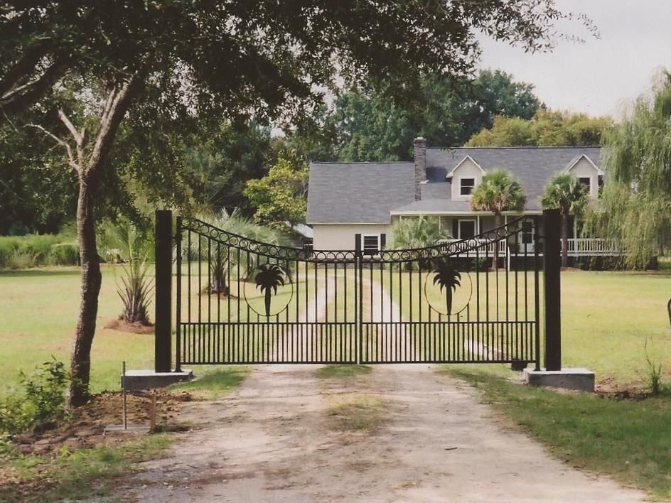 A gated driveway leading to a house with palm trees on it