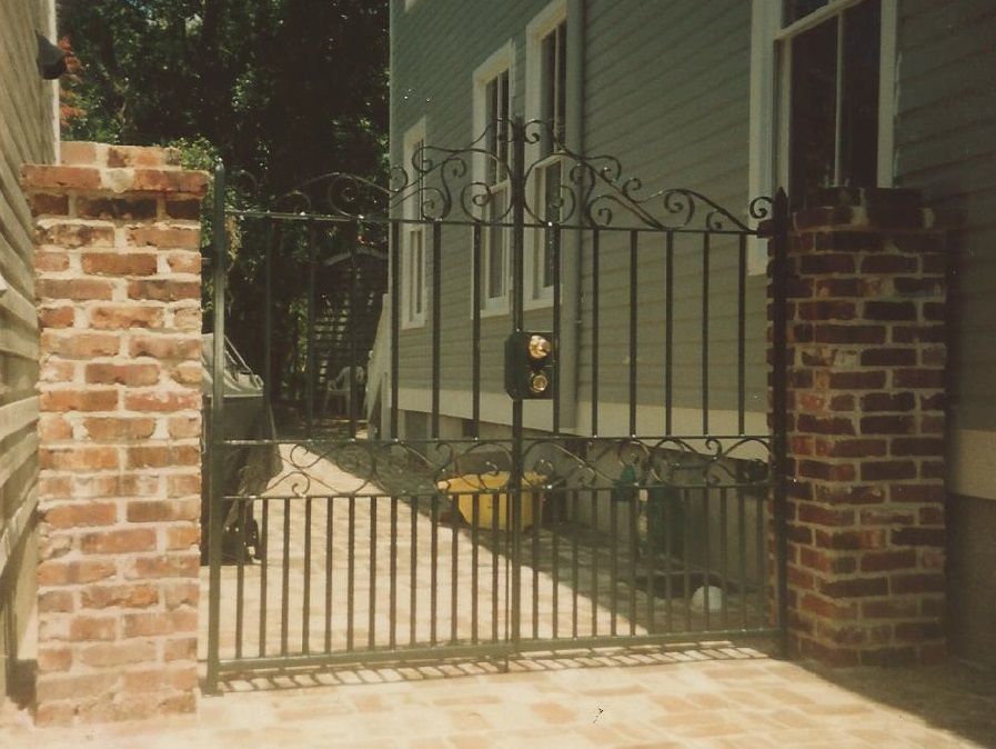 A wrought iron gate is surrounded by brick pillars