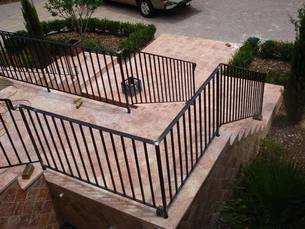 A staircase with a metal railing and a car parked in the background