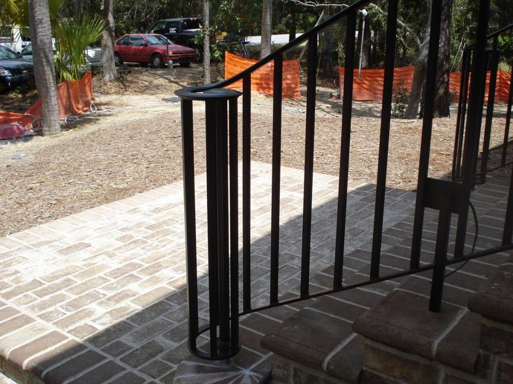 A brick walkway with a wrought iron railing