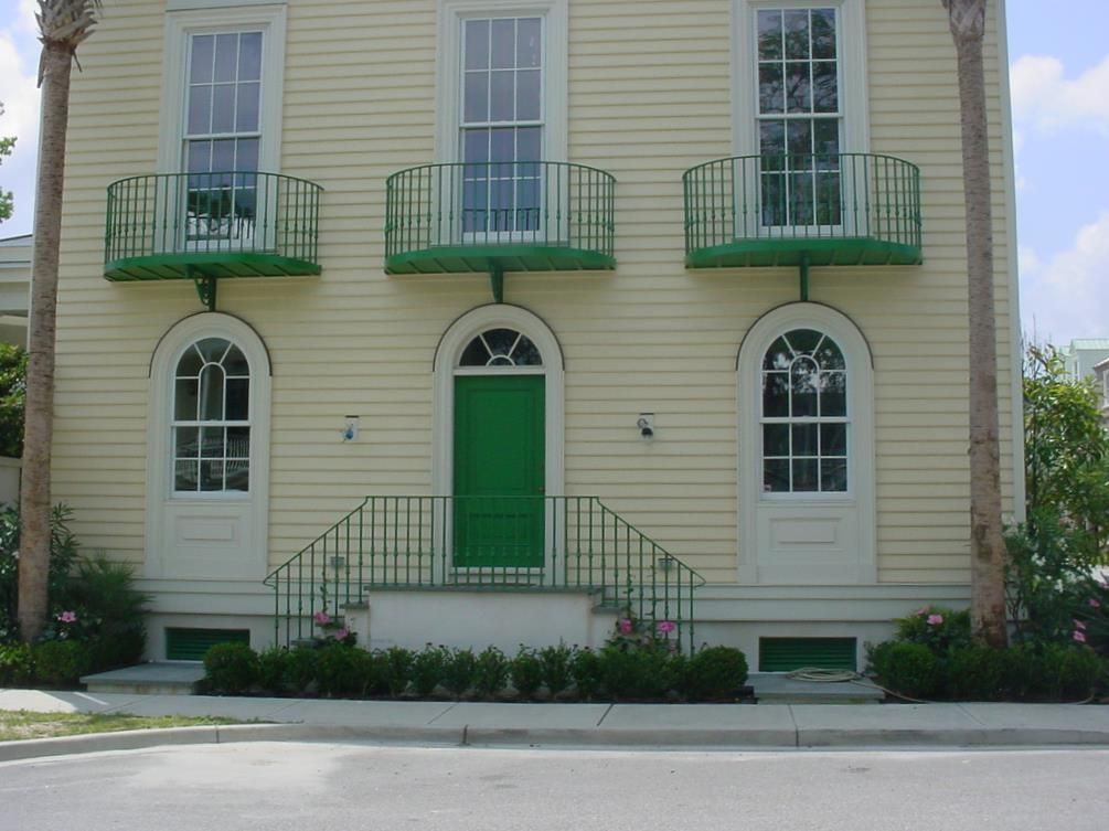 A yellow house with a green door and balconies