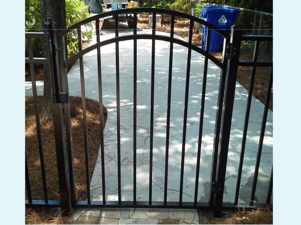 A black wrought iron gate leading to a concrete walkway