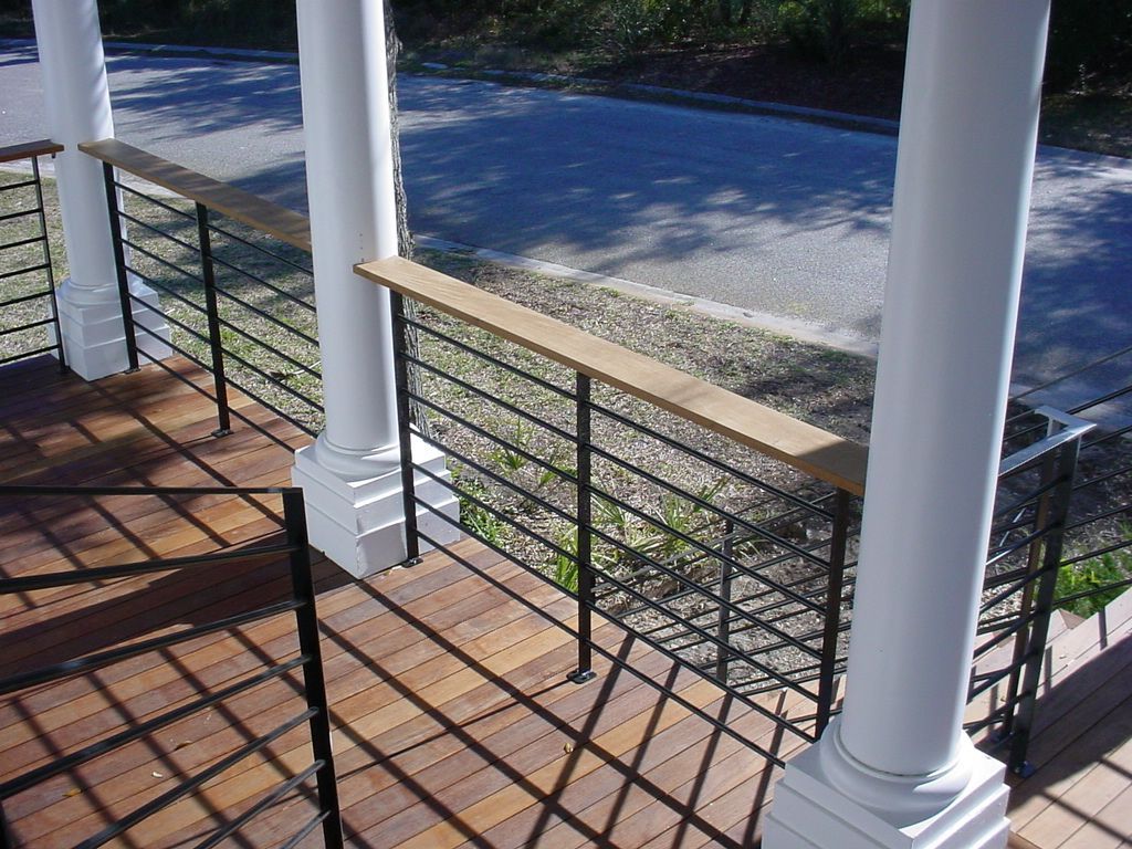 A balcony with a black railing and white columns