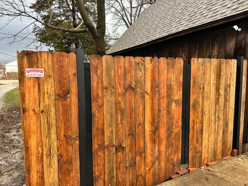 Orange wooden fence beside a dark barn, with a small sign on the left panel