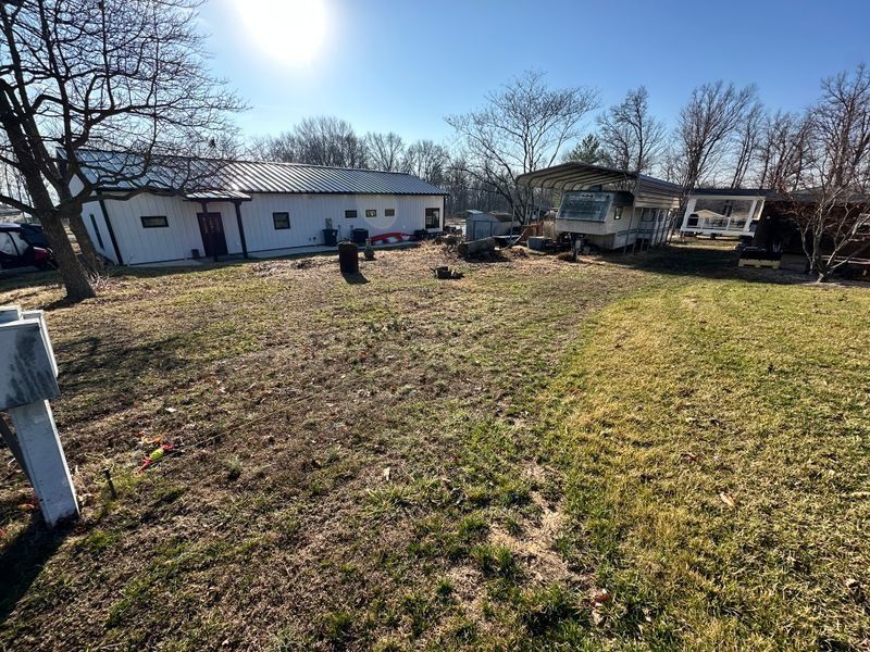 Backyard with a person mowing near white houses on a sunny day