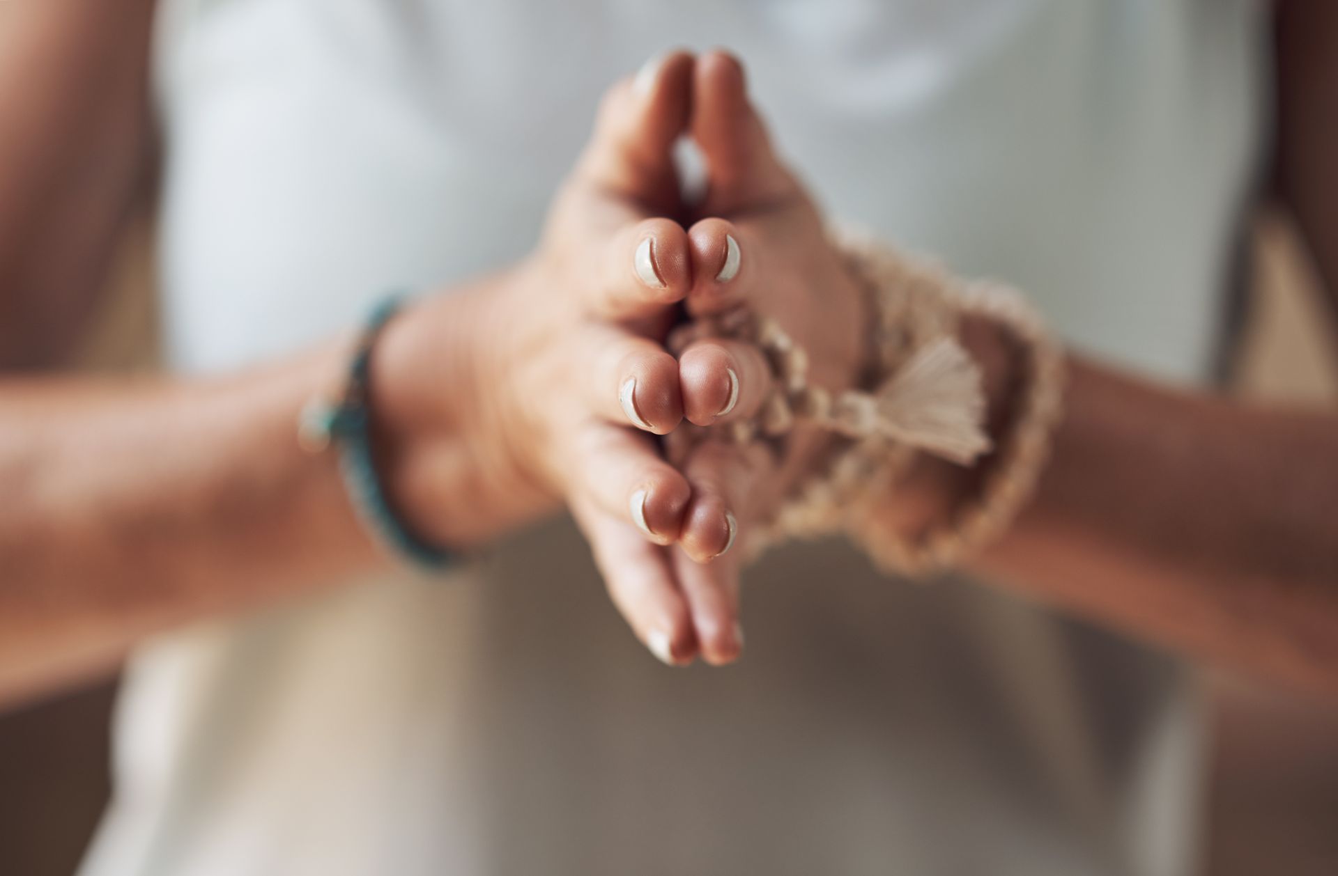 A woman is holding her hands together in a prayer position.