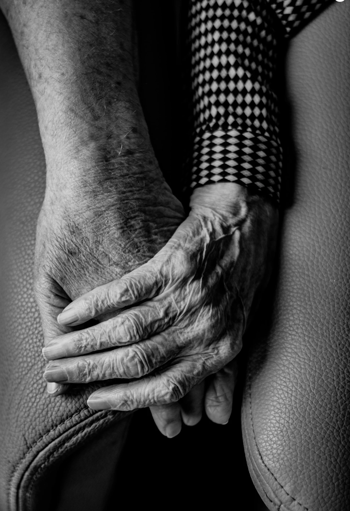 A black and white photo of a person holding another person 's hand.