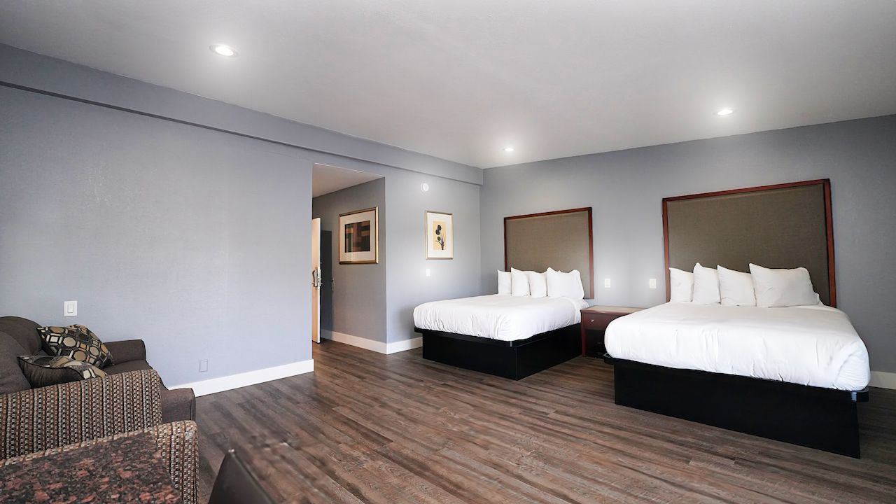 A hotel room with two beds , a couch , and a chair.