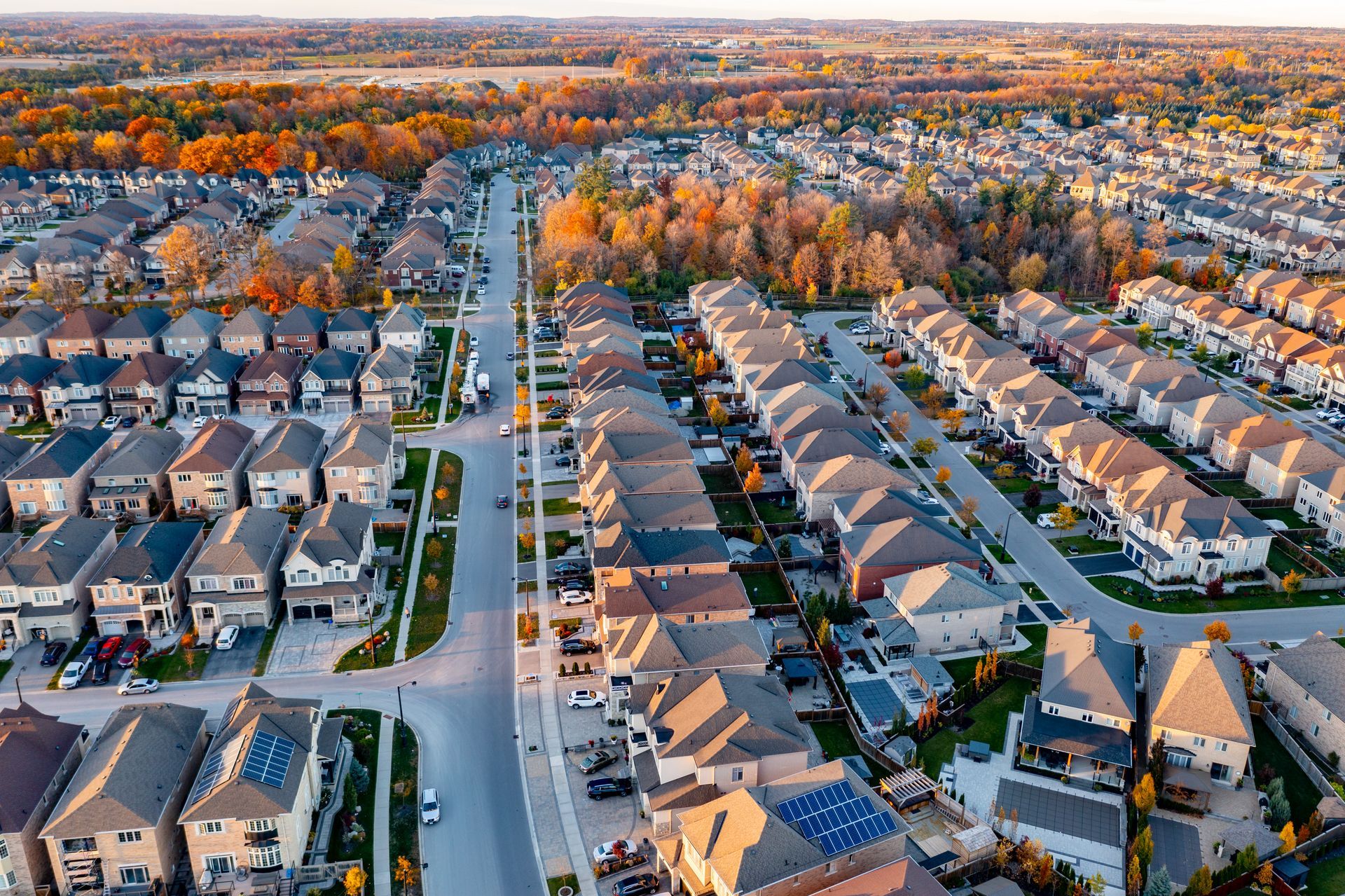 An aerial view of a residential area with lots of houses and solar panels on the roofs.