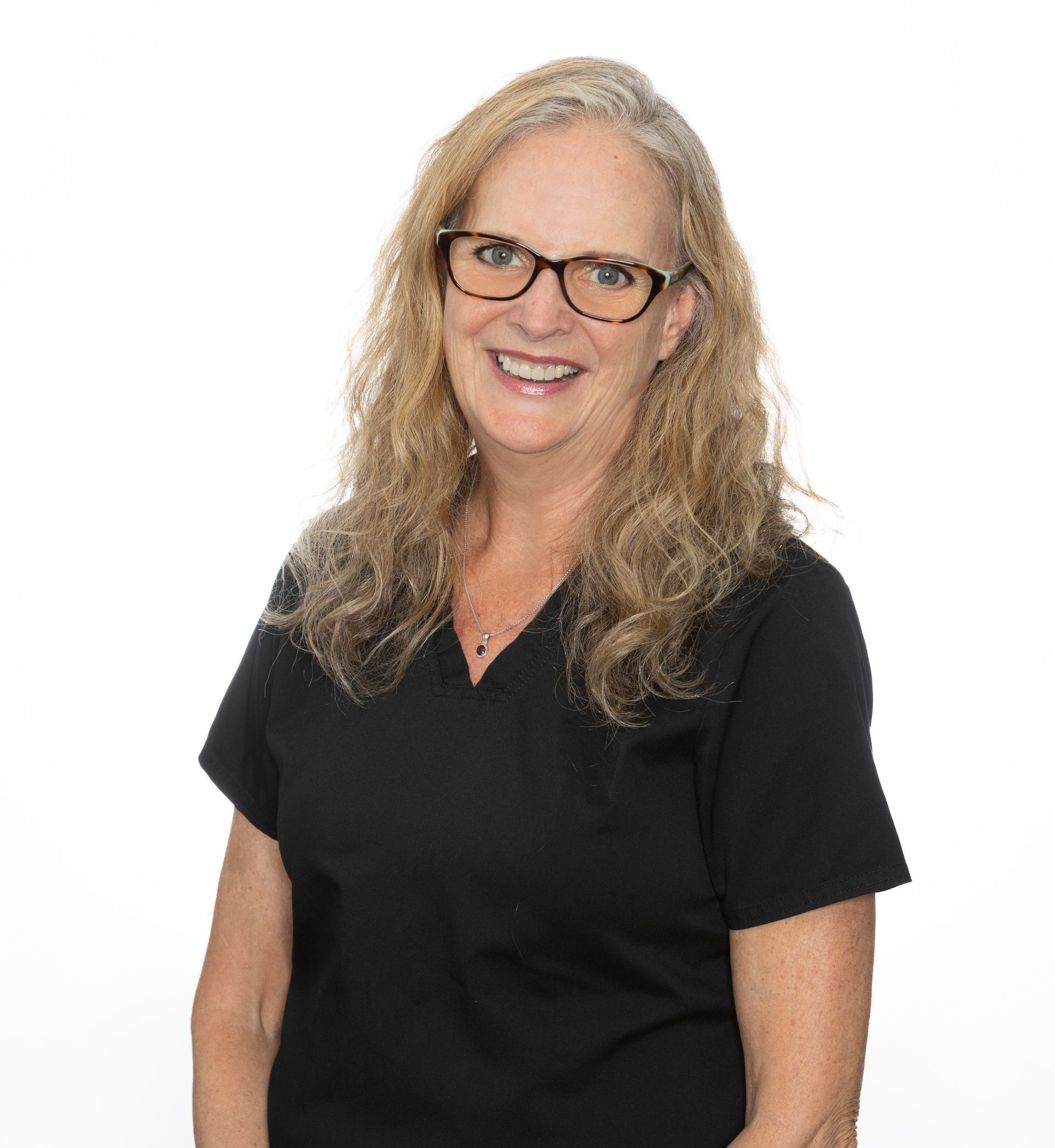 A woman in a blue scrub top is smiling for the camera