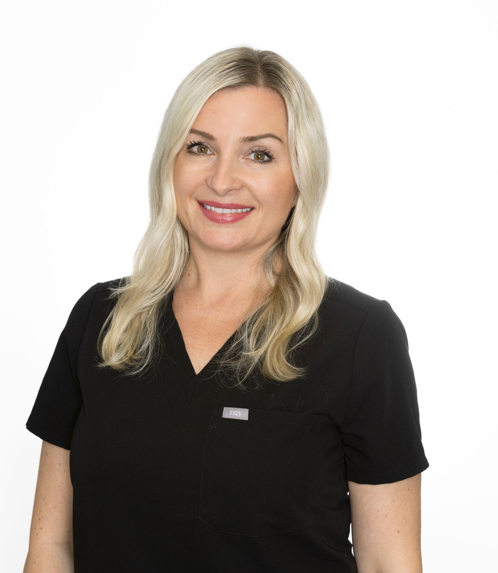 A woman in a blue scrub top is smiling for the camera