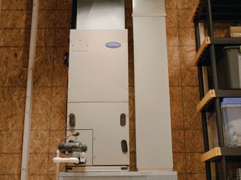 Large white industrial machine installed against plywood-framed wall in a workshop or utility room