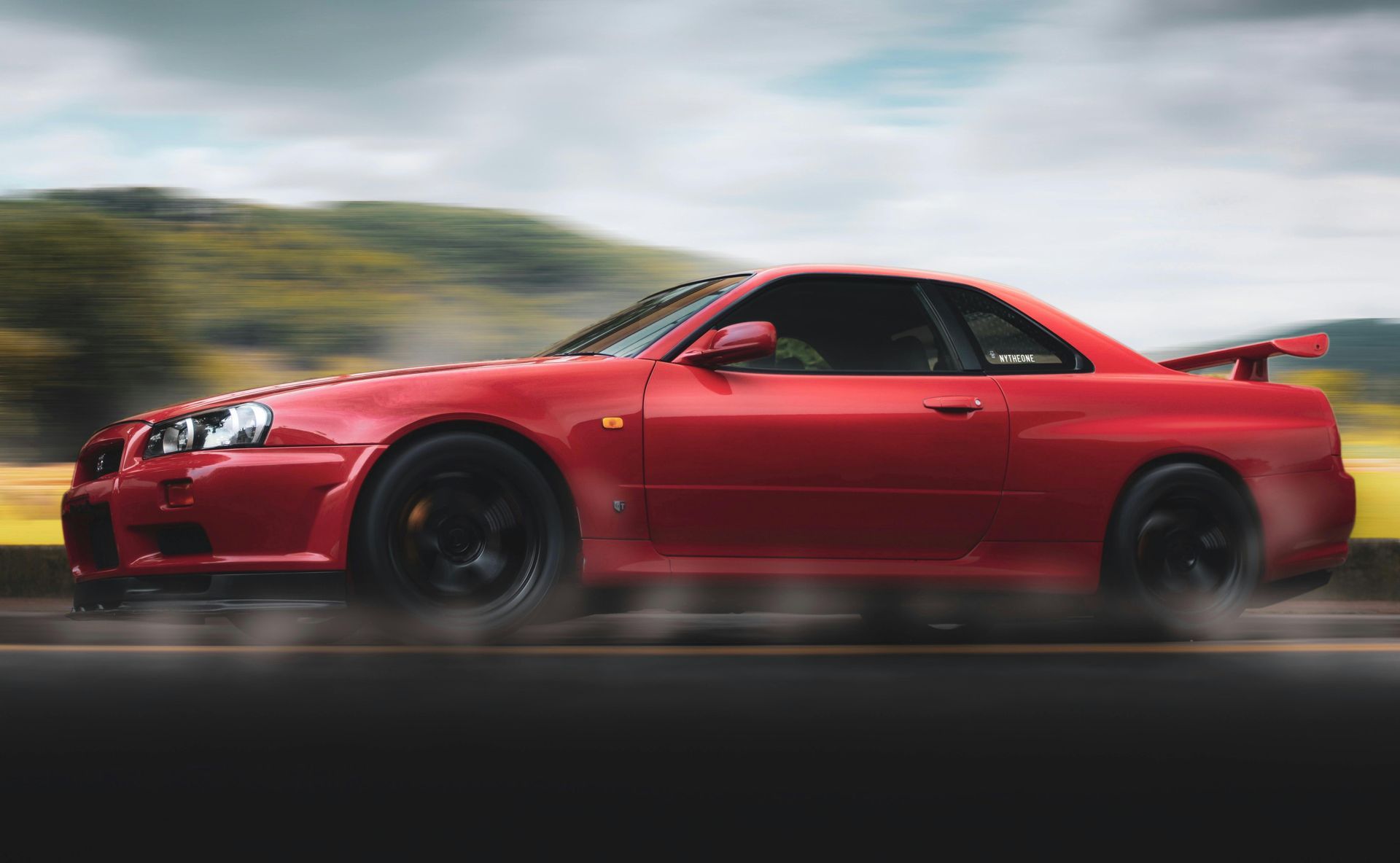 A red sports car is driving down a road.