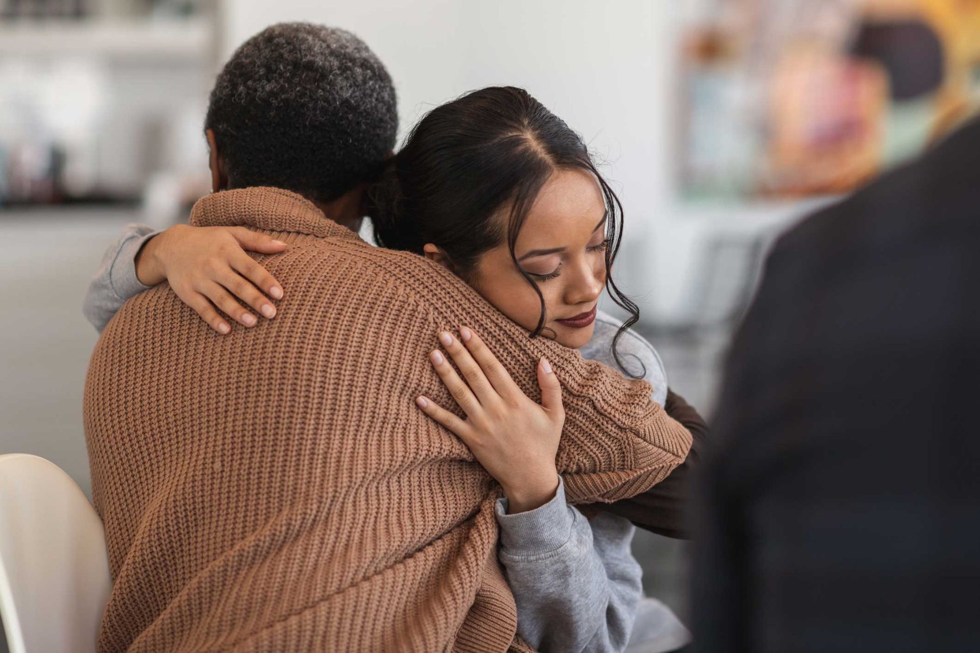 A woman is hugging a woman in a room.