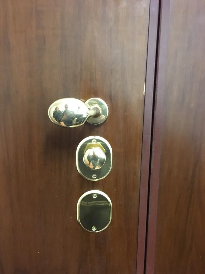 Serratura e catenaccio in ottone installati su una porta di legno.