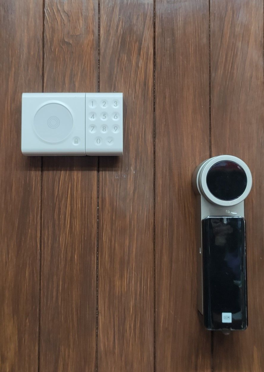 Una tastiera bianca e una serratura elettronica intelligente in bianco e nero montate su una porta a pannelli di legno verticali.