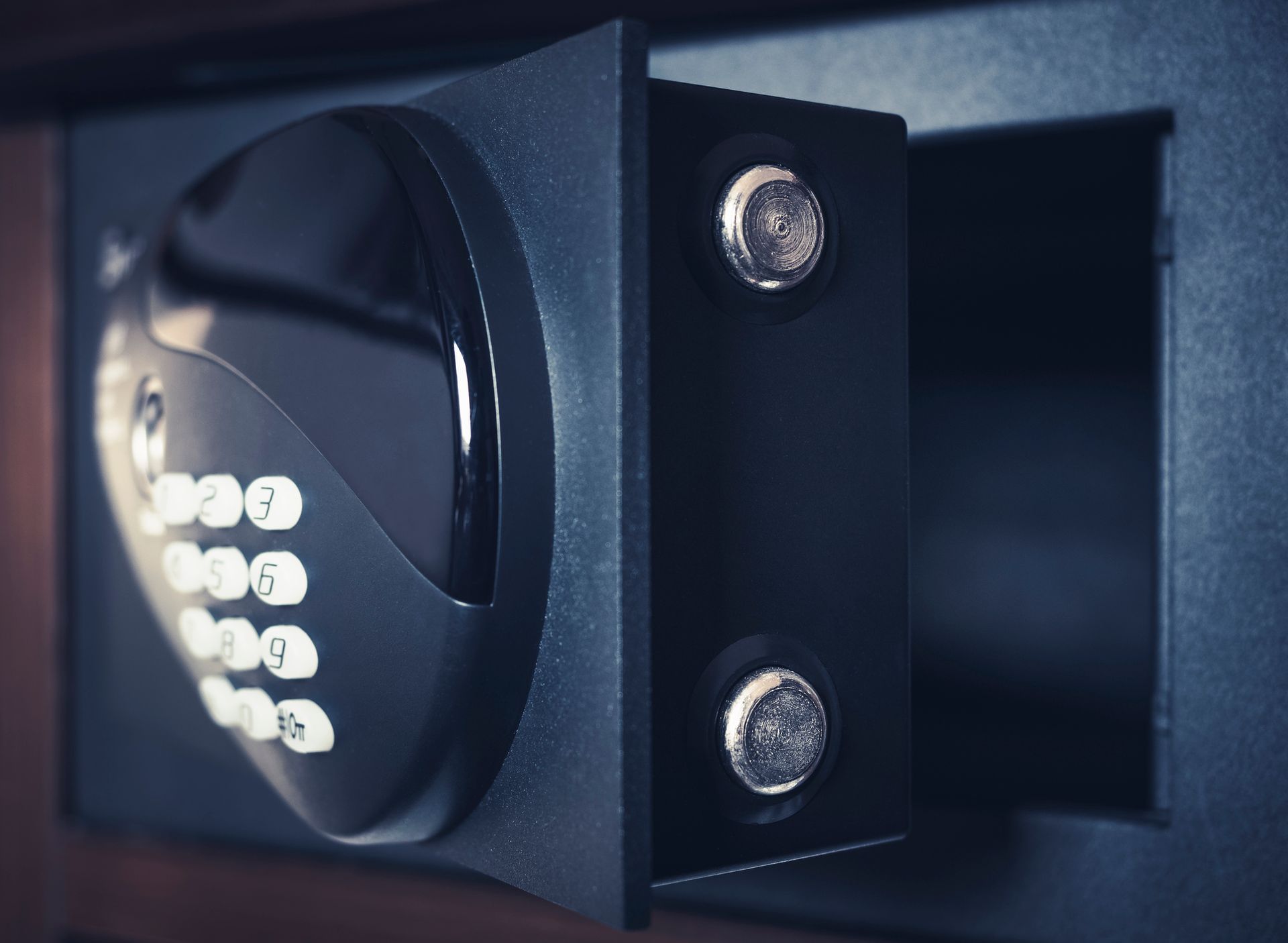 Sportello di cassaforte elettronica nero con tastiera e chiavistelli argentati, vista ravvicinata.