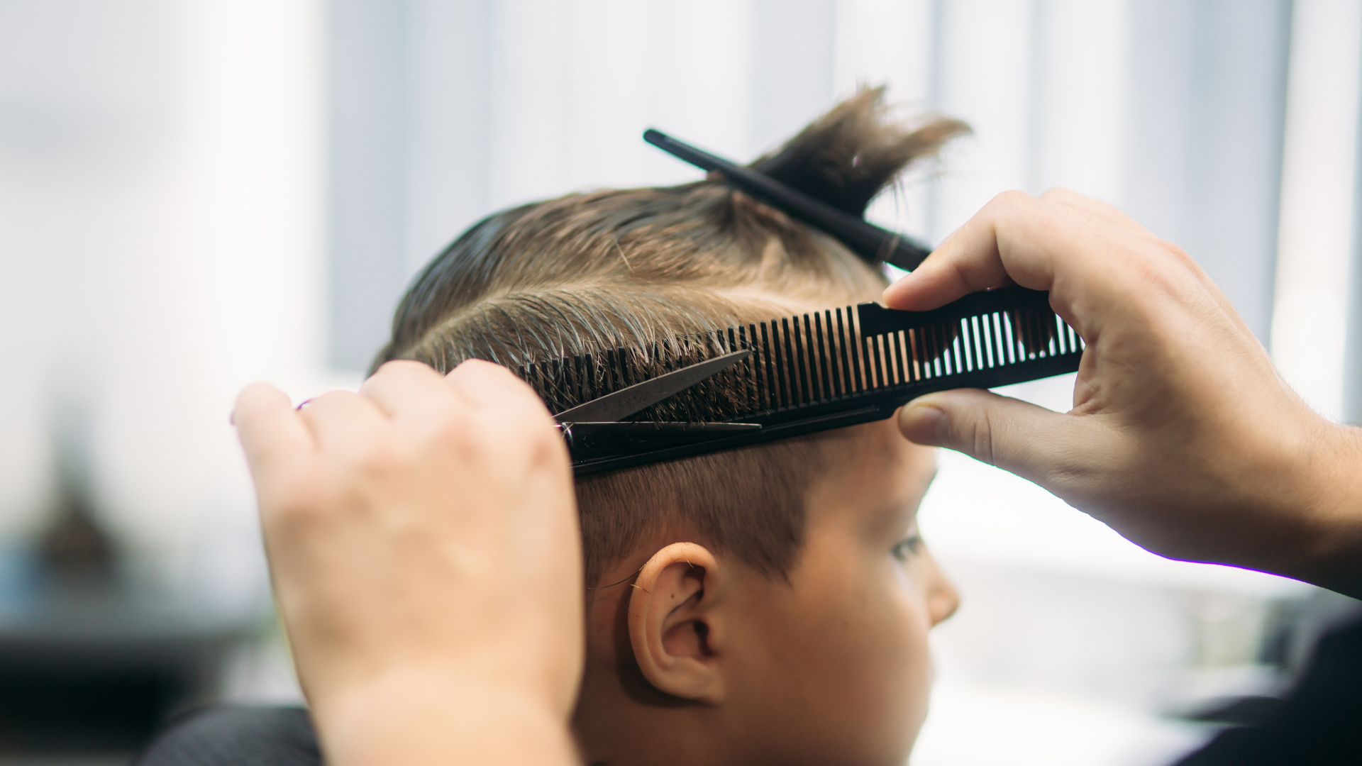 A young boy is getting his hair cut by a barber.
