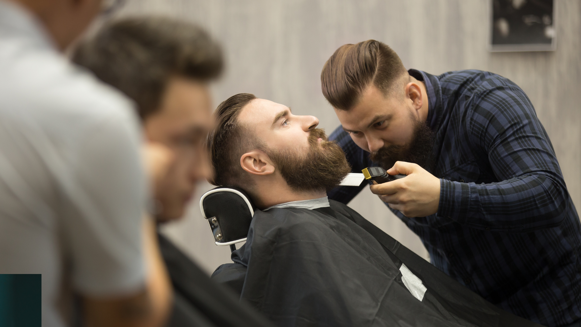 A man is getting his beard trimmed by a barber in a barber shop.