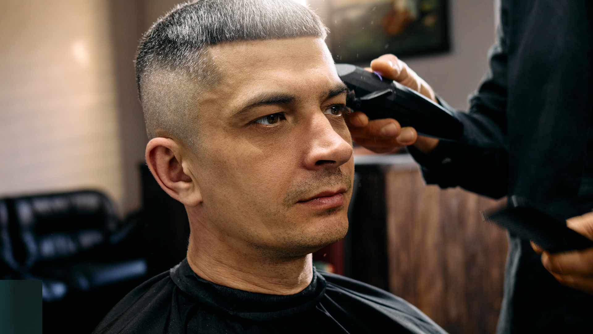 A man is getting his hair cut by a barber in a barber shop.