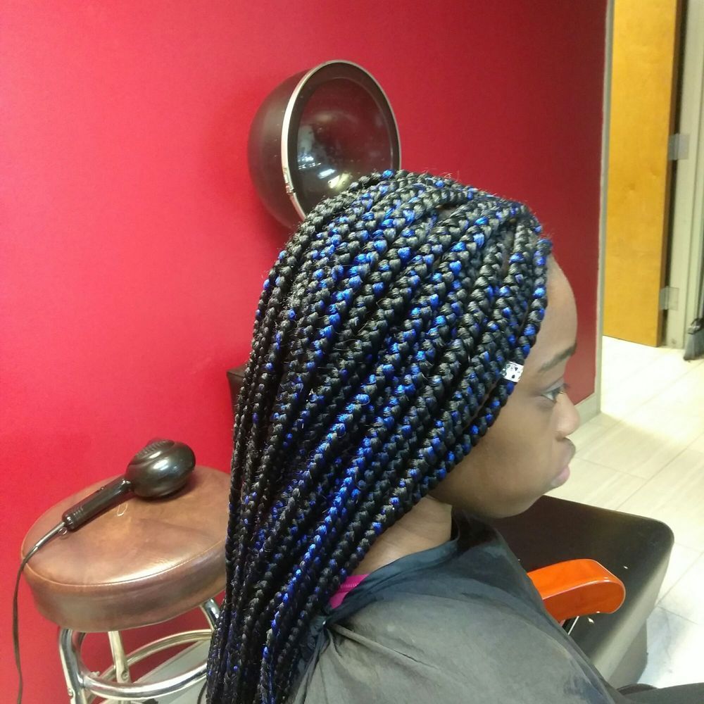 A woman with blue and black braids is sitting in a chair
