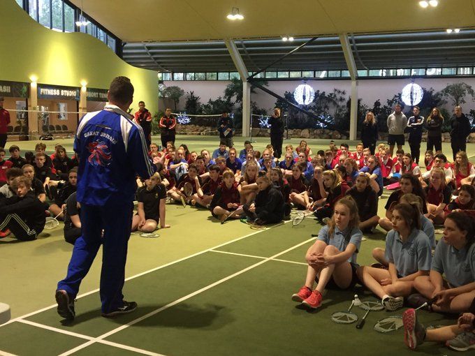 A man in a blue jacket stands in front of a large group of children