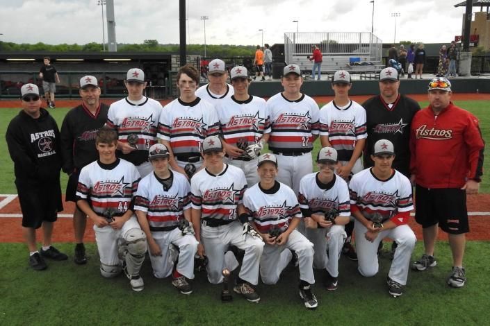 Youth baseball team posing for a group photo on a field, wearing white uniforms with red and black stripes.