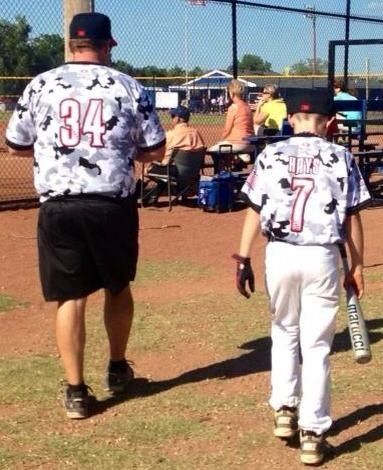 Youth baseball players and coach walking toward the dugout on a sunny field