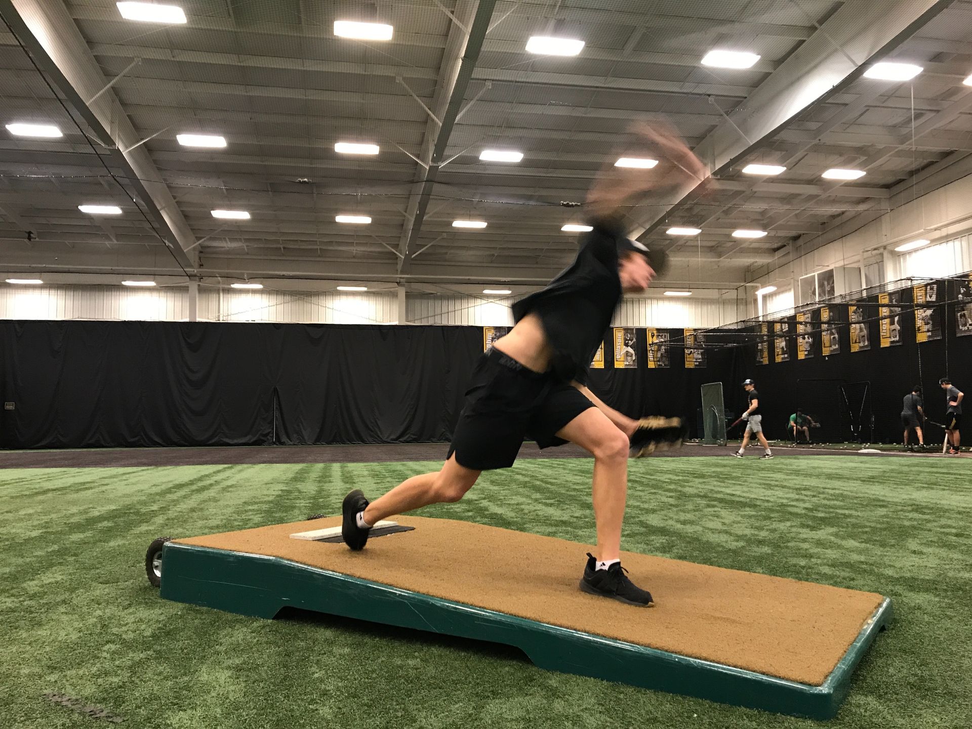 Athlete lunges on a slanted training ramp inside an indoor turf facility.