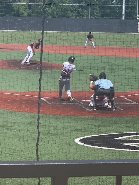 Baseball game in progress, batter at plate with pitcher and catcher set on a sunny field.