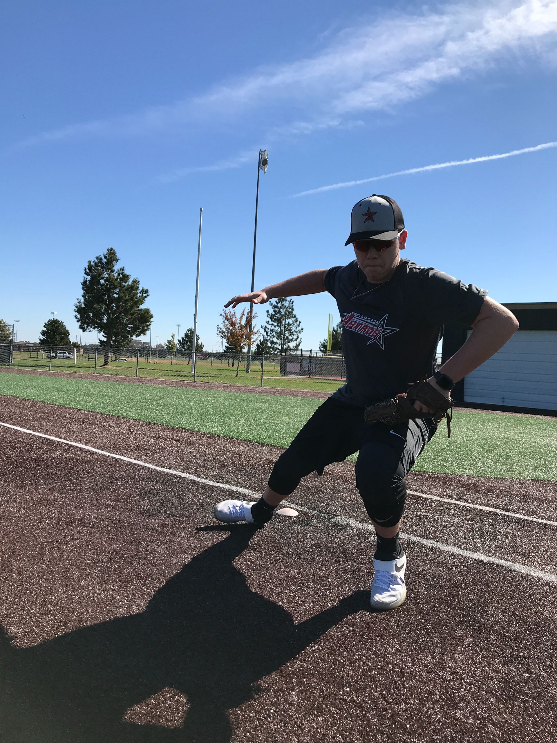 Person swinging a bat on a baseball field under a clear blue sky