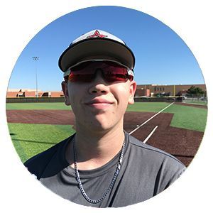 Young baseball player wearing a cap and sunglasses on a field under a blue sky