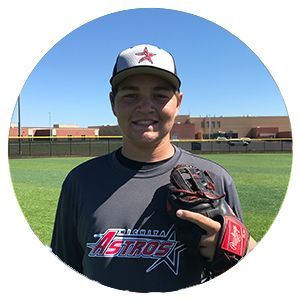 Young athlete in an Astros shirt holding a glove on a baseball field, smiling at the camera.