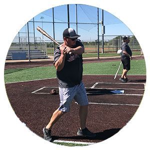 Baseball batter at home plate preparing to swing, with another player behind on the field.