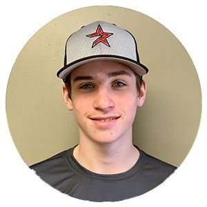 Person wearing a gray cap and dark shirt, smiling against a plain beige background