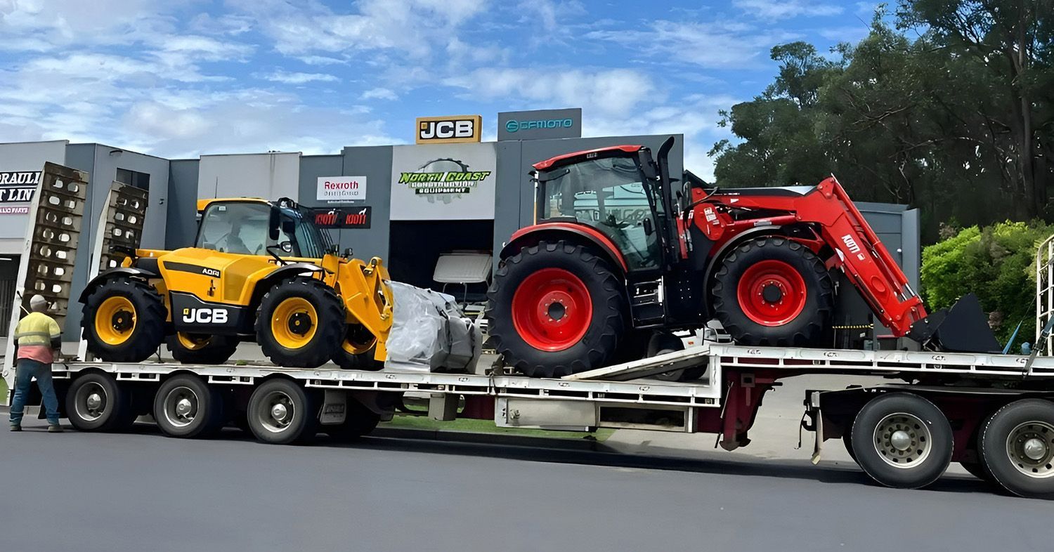 A Flatbed Truck Carrying A Yellow And A Red Tractor