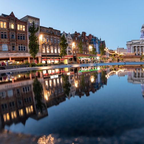 A row of buildings are reflected in a body of water