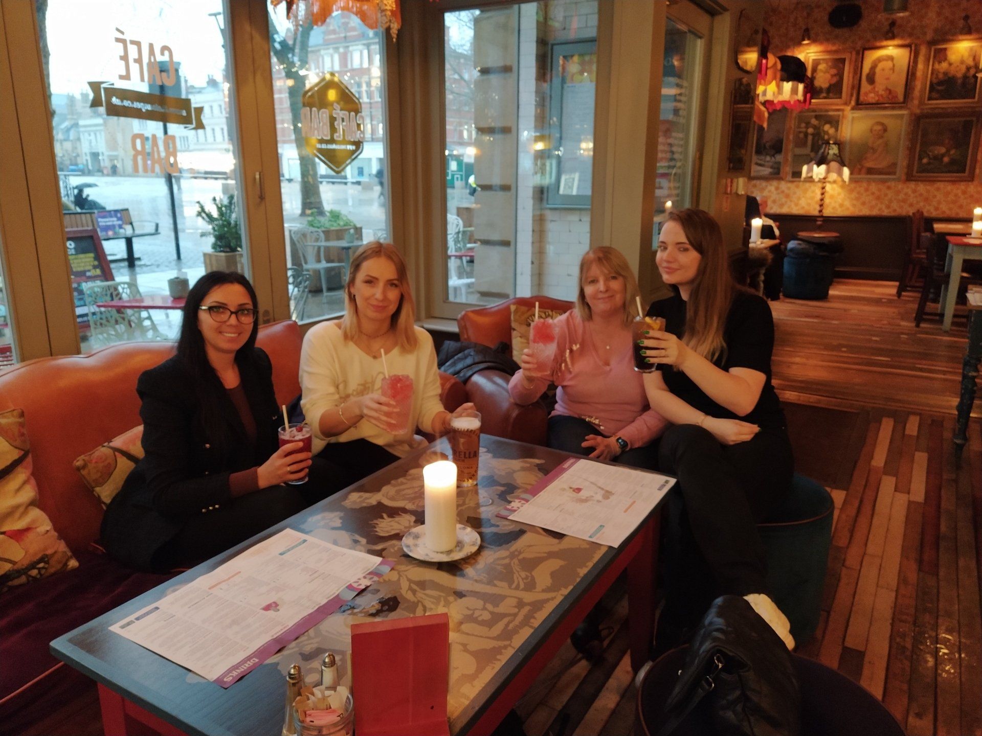 A group of women are sitting at a table in a restaurant toasting with drinks.