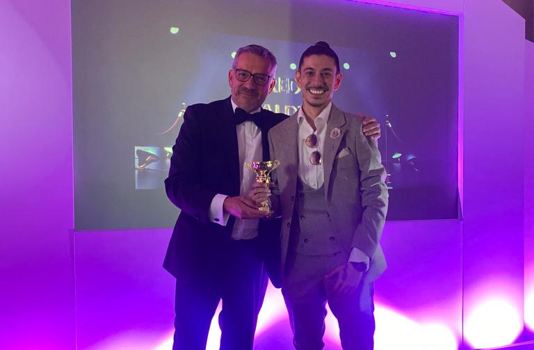 Two men in suits are standing next to each other in a room with purple lights.