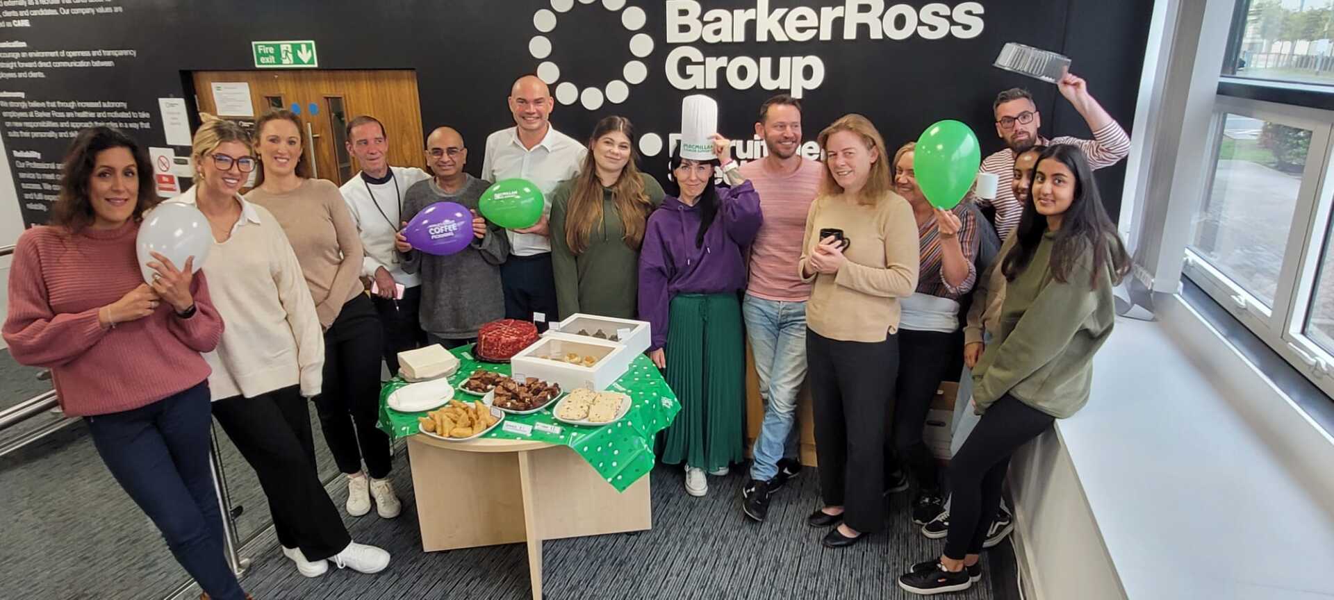 A group of people are posing for a picture in front of a barker ross group sign.