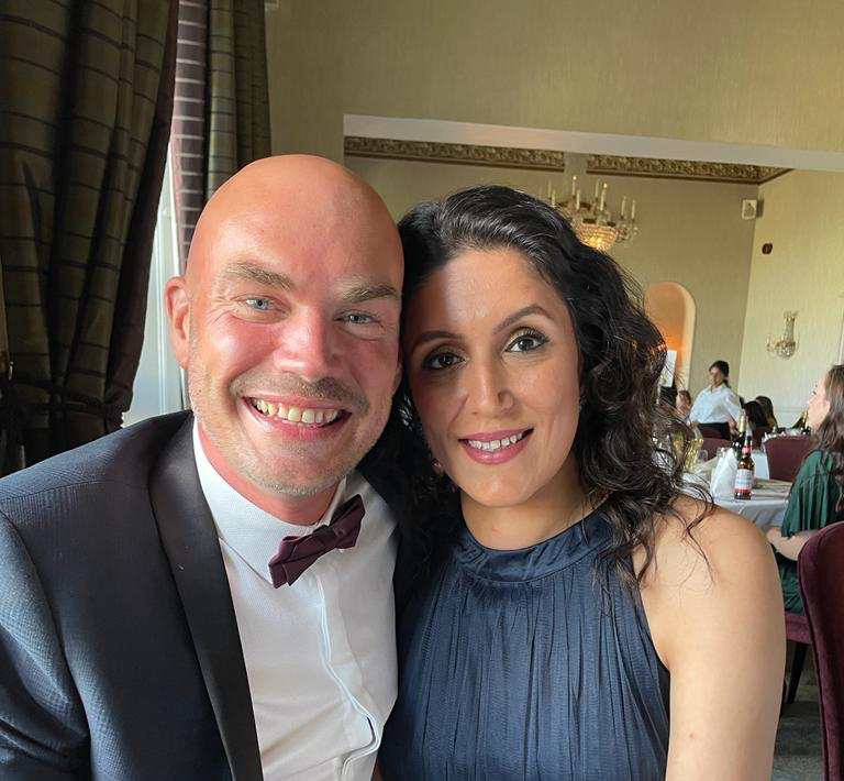 A man and a woman are posing for a picture in a restaurant.