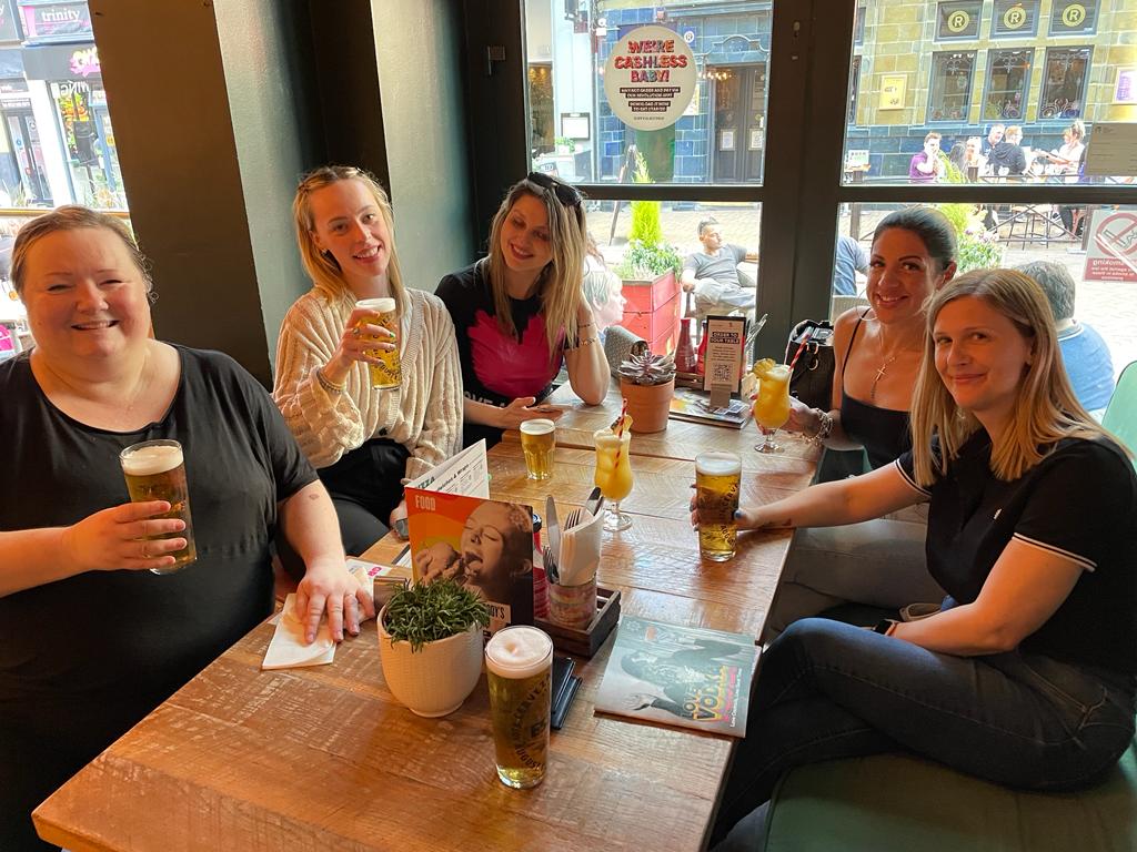 A group of women are sitting at a table drinking beer.