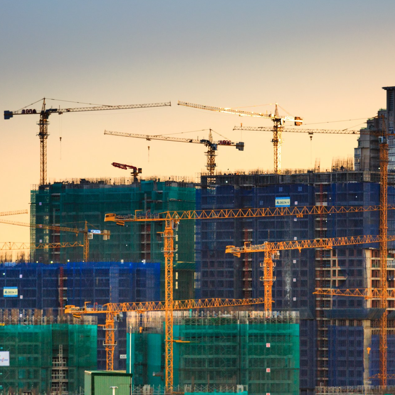 A construction site with lots of cranes and buildings under construction