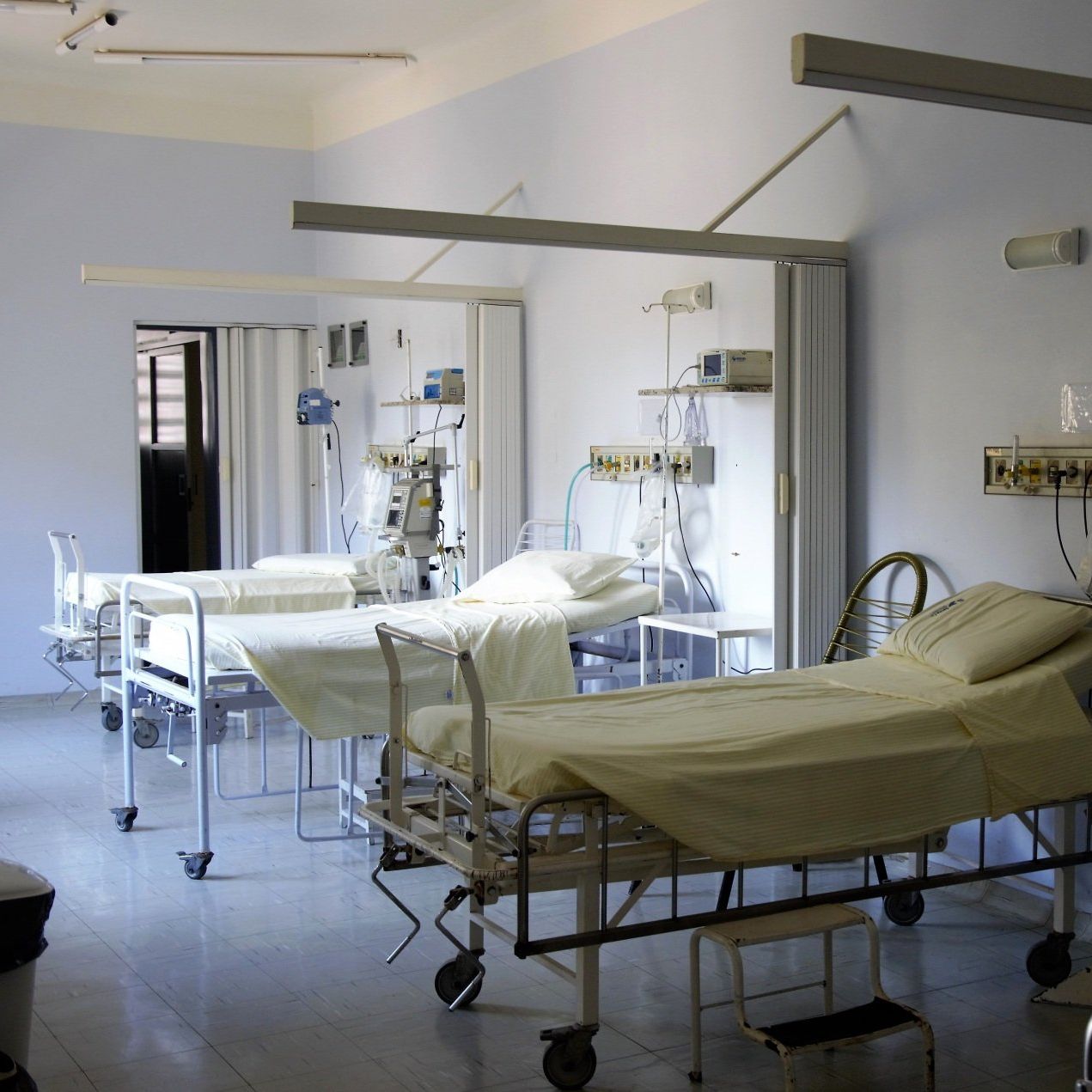 A row of hospital beds with yellow sheets